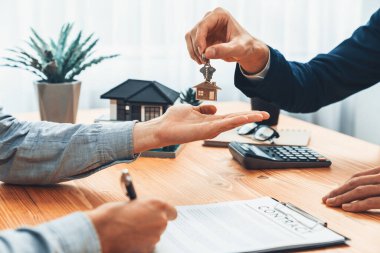 Emlakçı, ev kredisi toplantısı sırasında kira sözleşmesi imzaladıktan sonra ev anahtarını alıcıya veriyor. Yeni ev sahipliği için başarılı bir emlak satış anlaşması. Varlık