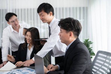 Harmony in office concept as business people analyzing dashboard paper together in workplace. Young colleagues give ideas at manager desk for discussion or strategy planning about project.