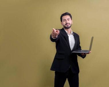 Yenilikçi teknoloji kavramına sahip başarılı bir iş adamı, kamerayı işaret eden ve dizüstü bilgisayarı tutan ve reklam ya da promosyon için arka planda heyecanla gülümseyen. Coşkulu