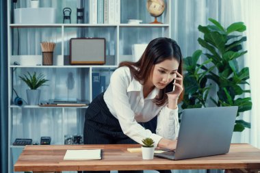 Genç hevesli iş kadını iş görüşmesinde konuşuyor ve laptopuna çoklu ofis hanımı olarak notlar yazıyor. Müşterilerle telefonda konuşurken iş ödevleri yazan kadın çalışan.