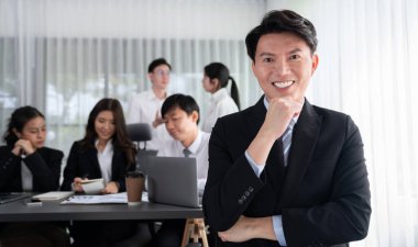 Portrait of focus young successful confident male manager, executive wearing business wear in harmony office arm crossed with blurred meeting background of colleagues, office worker.