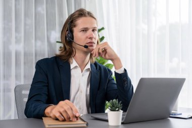 Erkek müşteri hizmetleri operatörü ya da telesales temsilcisi ofiste oturuyor, kulaklık takıyor ve müşteriyle satış desteği ya da kapanış konuşması yapıyor. Çağrı merkezi portresi. Varlık
