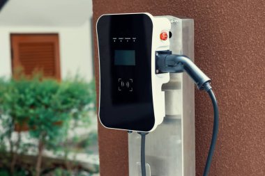 Progressive green energy-powered charging station concept for electric vehicle connected to home charging station at the garage or backyard. Eco friendly rechargeable car powered by clean energy.