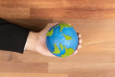 Üst düzey iş adamları kağıt toprağı masanın üstünde tutarlar. Temiz enerji ve sıfır CO2 emisyonu kullanan sürdürülebilir dünya için çevre bilinci. Yeşil politikası olan çevre dostu bir şirket. Değiştir