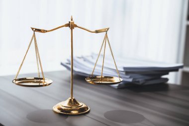 Parlak altın dengeli ölçek ve hukuk bürosundaki yasal kağıt yığını konsept adalet ve hukuki sembol olarak masanın üzerinde. Avukat ve avukatın adil ve eşitlik kararı için terazi uygulayın. denge