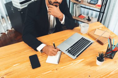 Modern ofis masasındaki modern profesyonel iş adamı çalışmak ve notlar yazmak için dizüstü bilgisayar kullanıyor. Ofisinde bilgisayar defteri üzerinde çalışan çalışkan bir ofis çalışanı. coşkulu