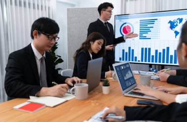 Confidence and asian businessman give presentation on financial analyzed by business intelligence in dashboard report to other people in board room meeting to promote harmony in workplace.