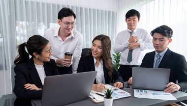 Harmony in office concept as business people analyzing dashboard paper together in workplace. Young colleagues give ideas at manager desk for discussion or strategy planning about project.