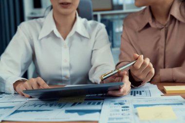 Analist ekip arkadaşı dijital gösterge panelinde finansal verileri tartışır, grafikleri dizüstü bilgisayar ve tablet ekranda analiz eder. Modern ofis pazarlama planlamak için iş zekasını kullanır. Coşkulu.