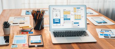 Dizüstü bilgisayar ekranında web ya da mobil uygulama UI UX için dijital ve kağıt kablo tasarımları. Beyin fırtınası ve tasarım uygulama çerçevesi için geliştirici çalışma alanının panoramik görüntüsü. İnceleyin