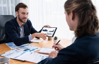 Ofisteki analist ekibi, iş performansını artırmak için tablet ekranında grafik ve grafik olan BI panelini kullanarak çalışma alanındaki pazarlama stratejisi için finansal veri analizi yapmakla meşgul. Varlık