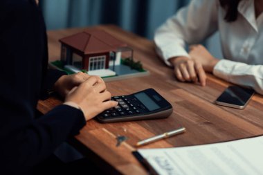 Temsilciyle ev kredisi sözleşmesini gözden geçiriyorum. Mali belgeleri ve vergi oranlarını, mülkiyet sahibi olmak için hesap makinesiyle analiz ediyorum. Yeni ev alımı ve finansman için anahtar imza. Coşkulu.