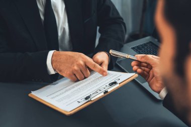 Kapanış toplantısı, iş adamı sözleşmenin şartlarını ve şartlarını dikkatle gözden geçiriyor. Şirket avukatı sözleşme anlaşmasında danışmanlık yapar. Coşkulu