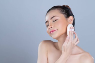 Glamorous beautiful female model applying cushion powder for facial makeup concept. Portrait of flawless perfect cosmetic skin woman put powder puff on her face in isolated background.