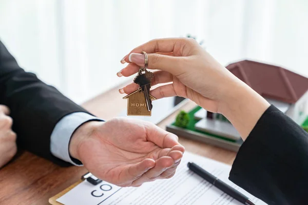 stock image Real estate agent handing house key to buyer after successful signing house loan contract. Landlord hand over house key to client. Entity