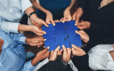 Çeşitli şirket çalışanları, ortaklık ve takım çalışmasını temsil etmek için bulmaca parçalarını birleştirerek ofiste işbirliği yapıyor. Yapboz 'u birleştirerek iş dünyasındaki birlik ve sinerji. Uyum