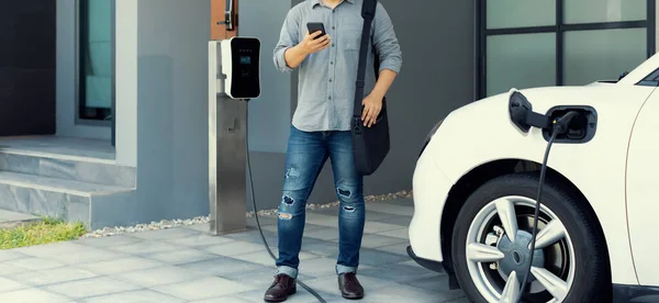 Progressive Asian Man Electric Car Home Charging Station Concept Use — Stockfoto