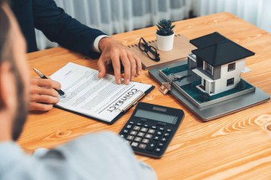 Müşteri ve emlakçı kredi sözleşmesini gözden geçirir, terimleri, faiz oranlarını ve mülkiyet haklarını tartışır. Yasal belgeleri analiz et ve karar vermeden önce anlaşmayı iyice oku. Varlık