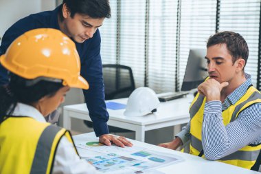 Engineers and competent employer discussing plans and blueprints together with tablet in the office. Concept of team contribution of ideas for engineering project.