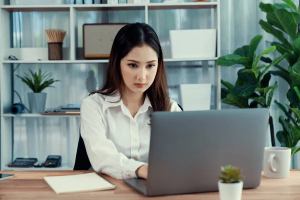 ラップトップを使用してコーヒーを飲みながら作業する現代のオフィスデスクで若いアジアの熱狂的なビジネス女性 勤勉で魅力的なオフィスの女性は彼女のオフィスワークスペースでコンピュータノートブックに取り組んで — ストック写真