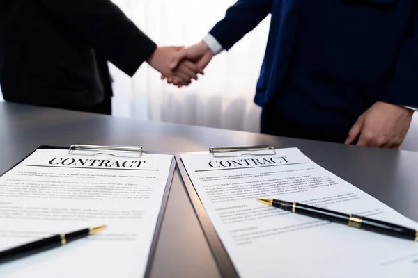 重点关注全景商业合同文件与笔 而两名专业人员握手模糊的背景 意味着成功的谈判和伙伴关系协议与握手 — 图库照片