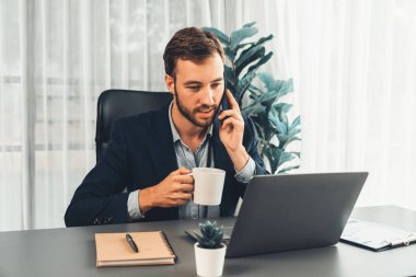 Çalışkan ve çalışkan iş adamı, cep telefonuyla müşterileriyle konuşurken, modern çoklu görev yapan ofis çalışanı yaşam tarzını sergiliyor. Varlık