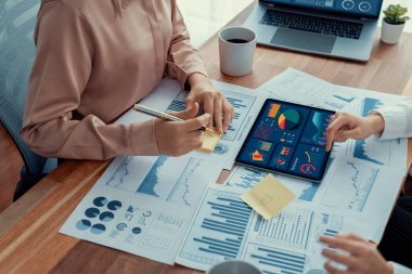 Analist ekip arkadaşı dijital gösterge panelinde finansal verileri tartışır, grafikleri dizüstü bilgisayar ve tablet ekranda analiz eder. Modern ofis pazarlama planlamak için iş zekasını kullanır. Coşkulu.