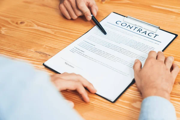 ビジネスマンは企業パートナーシップの契約書を注意深くレビューします 専門的なビジネスの決定のための会議のテーブルの顧客の読書契約の契約および条件 エンティティ — ストック写真