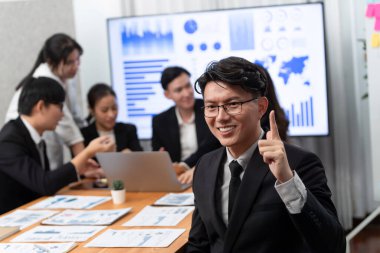 Focus portrait of successful confident male manager or executive in business wear with blurred background of businesspeople, colleagues working with financial report papers in office of harmony.