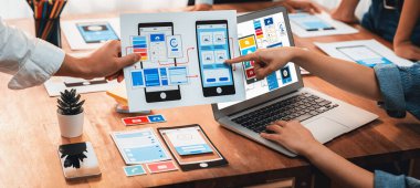 Dizüstü bilgisayar ekranında mobil uygulama için UI ve UX tasarımları tasarlayan ön uç geliştirici ekibin panorama görüntüsü. Kullanıcı dostu UI tasarımı için kullanıcı arayüzü geliştirme ekibi planlama. İnceleyin