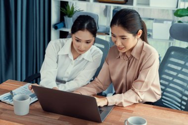 Modern ofis çalışma alanında iş birliği yapan iki genç ofis çalışanı, modern ofis çalışanı olarak profesyonelliklerini sergileyerek, dizüstü bilgisayarda tartışıyorlar ve birlikte çalışıyorlar. Coşkulu.