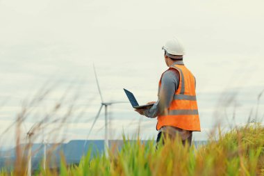 Kırsal kesimdeki bir tepenin tepesinde ya da dağda rüzgar çiftliğinde çalışan bir mühendis. Yenilenebilir ve sürdürülebilir enerjinin gelecekteki üretimi için yenilikçi bir ideal. Rüzgar türbininden enerji üretimi.