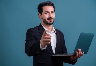 Yenilikçi teknoloji kavramına sahip başarılı bir iş adamı, kamerayı işaret eden ve dizüstü bilgisayarı tutan ve reklam ya da promosyon için arka planda heyecanla gülümseyen. Coşkulu