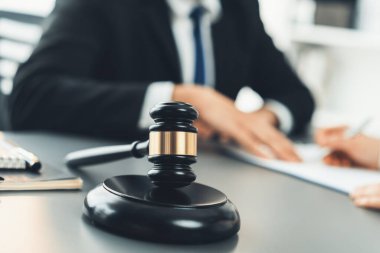 Hukuk bürosunun masasında yasal evraklarla çalışan avukatın bulanık arkaplanına odaklanın. Kanun yapıcı ve avukatın adil ve adil yargılaması için meşru çekiç. Eşitlik