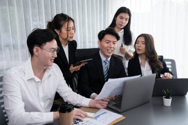 Harmony in office concept as business people analyzing dashboard paper together in workplace. Young colleagues give ideas at manager desk for discussion or strategy planning about project.