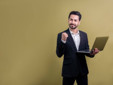Yenilikçi teknoloji kavramına sahip başarılı bir iş adamı, ayakta duran, dizüstü bilgisayarı tutan ve telif alanı arka planında reklam ya da tanıtım için heyecanla gülümseyen. Coşkulu