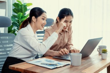 Modern ofis çalışma alanında iş birliği yapan iki genç ofis çalışanı, modern ofis çalışanı olarak profesyonelliklerini sergileyerek, dizüstü bilgisayarda tartışıyorlar ve birlikte çalışıyorlar. Coşkulu.