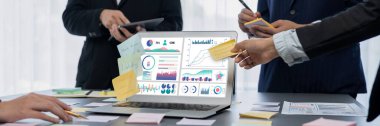 Analizci ekibi yaratıcı ve analitik beyin fırtınası fikri için bilgisayar ekranında BI veri paneli olan yapışkan bir not kullanıyor. Pazarlama stratejisi için finansal veri görselleştirme teknolojisini analiz et. Dahi.