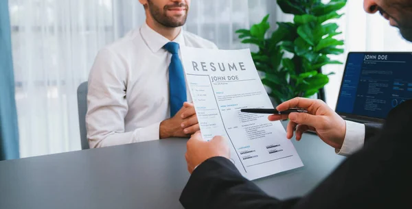 Interviewing job applicant in office with resume paper. Candidate wear suit for formal conversation with interviewer. Recruitment process with question about career and work experience. Fervent