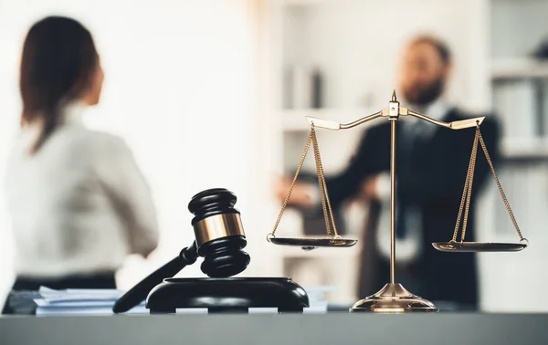 Balanced scale of justice and gavel hammer in focus on blurred background of lawyer colleagues discuss and plan for lawsuit in law firm office, as legal representatives. Equilibrium