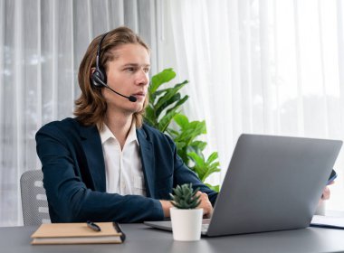 Erkek müşteri hizmetleri operatörü ya da telesales temsilcisi ofiste oturuyor, kulaklık takıyor ve müşteriyle satış desteği ya da kapanış konuşması yapıyor. Çağrı merkezi portresi. Varlık