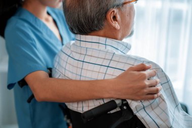 Rear view of a caregiver and her contented senior patient gazing out through the window. Elderly illness, nursing homes for the elderly, and pensioner life