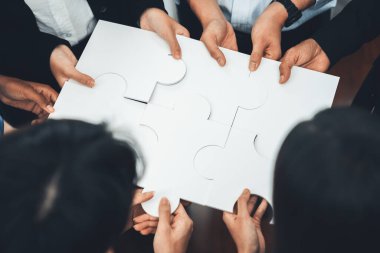 Çeşitli şirket çalışanları, ortaklık ve takım çalışmasını temsil etmek için bulmaca parçalarını birleştirerek ofiste işbirliği yapıyor. Yapboz 'u birleştirerek iş dünyasındaki birlik ve sinerji. Uyum