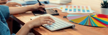 Grafik tasarımcısı, modern dijital stüdyo işyerinde profesyonel grafik ekibiyle benzersiz bir tasarım yaparken bilgisayar dizüstü bilgisayar ve grafik çizim kalemi üzerinde çalışır. Panorama çekimi. İnceleyin