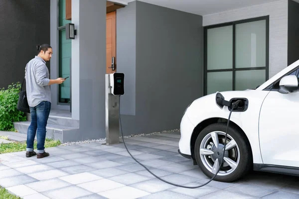 Progressive Asian Man Electric Car Home Charging Station Concept Use — Foto Stock