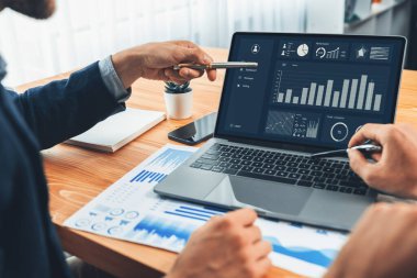 Ofisteki analist ekibi, iş performansını artırmak için bilgisayarında grafik ve çizelge olan BI gösterge panelini kullanarak çalışma alanındaki pazarlama stratejisi için finansal veri analizi yapmakla meşgul. Varlık