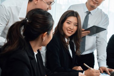 Harmony in office concept as business people analyzing dashboard paper together in workplace. Young colleagues give ideas at manager desk for discussion or strategy planning about project.