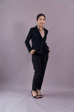 Kendine güvenen genç iş kadınının tüm vücut boyu resmi izole bir arka planda duruyor, resmi siyah takım elbise içinde poz veriyor. Ofisteki kadın ya da yönetici, zeki ve profesyonel görünümlü. Coşkulu.