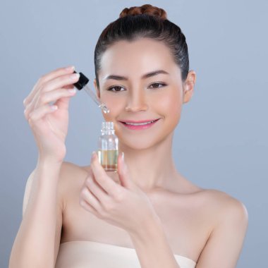 Glamorous portrait of beautiful woman applying extracted cannabis oil bottle for skincare product. CBD oil dropper pipette for cosmetology treatment and cannabinoids concept in isolated background.