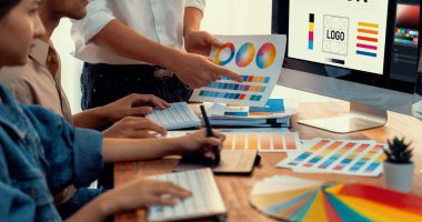 Grafik tasarımcısı, modern dijital stüdyo işyerinde profesyonel grafik ekibiyle benzersiz bir tasarım yaparken bilgisayar dizüstü bilgisayar ve grafik çizim kalemi üzerinde çalışır. Panorama çekimi. İnceleyin